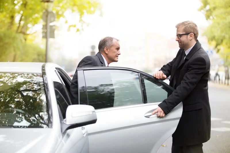 Chauffeur open car door for businessman getting out