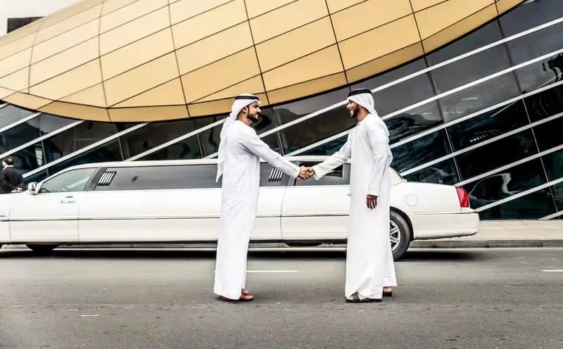 the two arabian man hand shake with each other in front of limousine in dubai