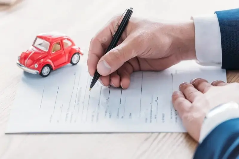 A person signing a car service agreement with a toy car, symbolizing private chauffeur car rental in Dubai.