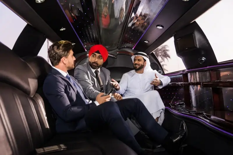 Three passengers seated inside a luxury limo, talking during their Dubai to Abu Dhabi car with driver journey about how long the travel will take